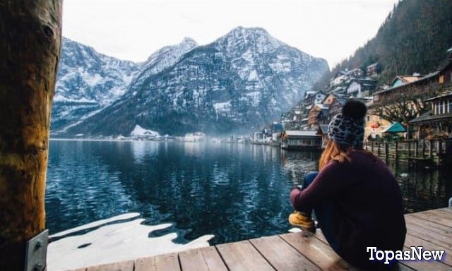 Девушка сидит и смотрит на горы и озеро - картинка